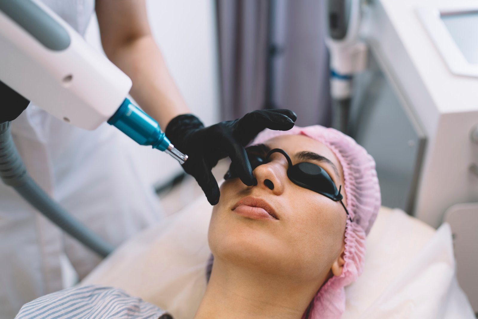 Patient receiving BBL laser facial treatment by a professional in gloves at a clinical spa.