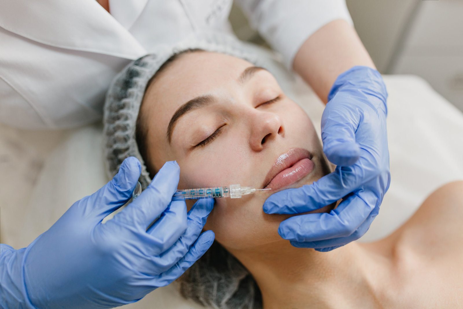 Patient receiving dermal filler injection on the face by a professional wearing gloves.